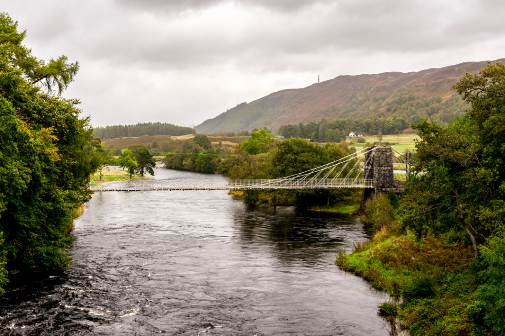 View of the historic taper suspension bridge of Oich hanging across the river at Aberchalder, Scotland